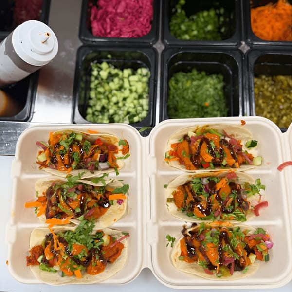 Six Indian tacos with orange chicken, cilantro, and dark sauce in a takeout container.