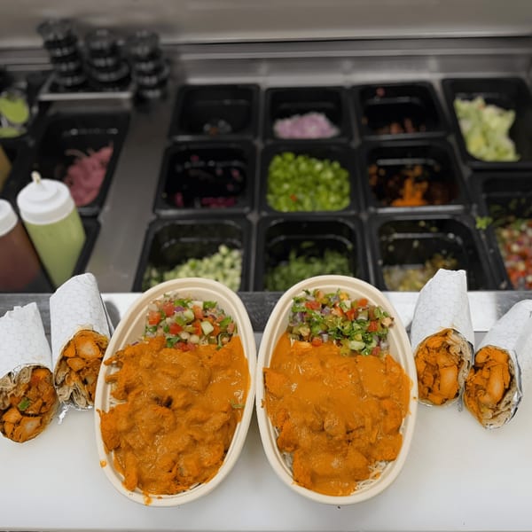 Two Tandoori Twist butter chicken bowls with salsa and two chicken wraps on a counter.