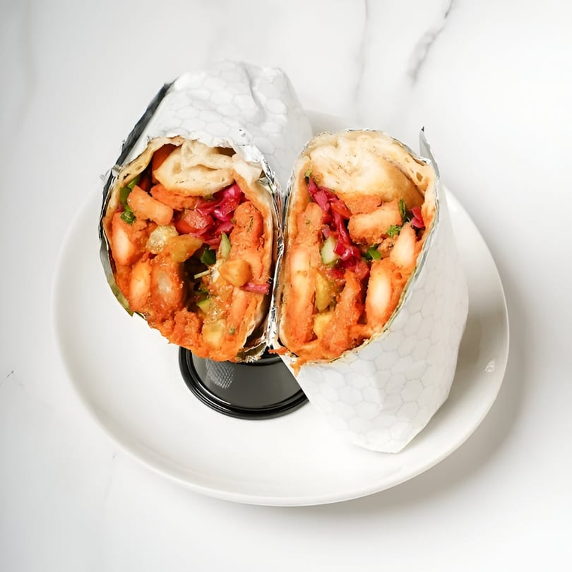 Two halves of a Tandoori Twist Indian Grub wrap, filled with orange chicken and red cabbage.