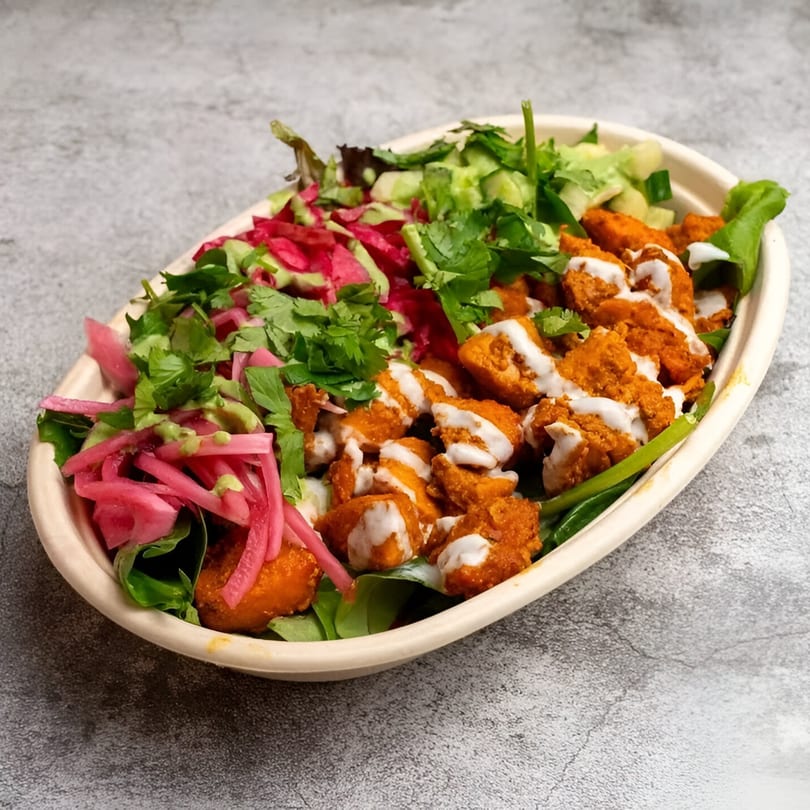 A Tandoori Twist Indian Grub bowl with chicken, pickled onions, cucumber, and cilantro.