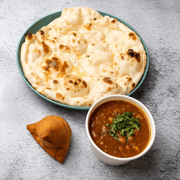 Tandoori Twist's naan bread on a teal plate, a samosa, and a bowl of chana masala.