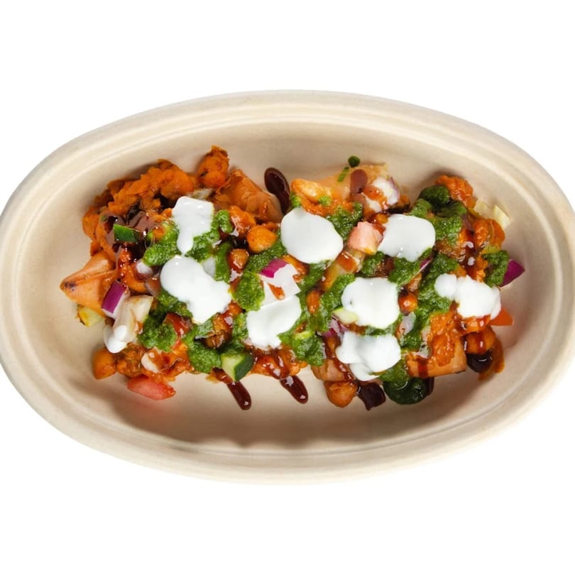 Indian chaat with green chutney, white yogurt, and dark sauce in an oval bowl.